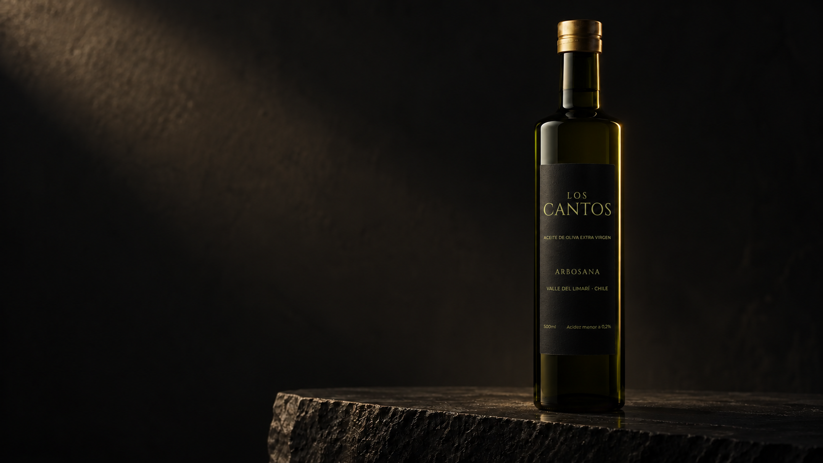 Botella de aceite Los Cantos con etiqueta frontal negra y dorada sobre piedra oscura